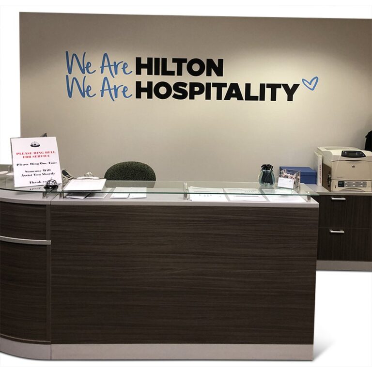 We Are Hilton lobby wall graphics behind a reception desk, produced by PLC Print